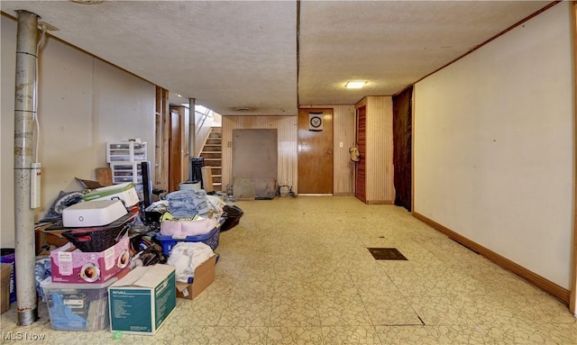 finished below grade area with tile patterned floors, stairway, baseboards, and a textured ceiling