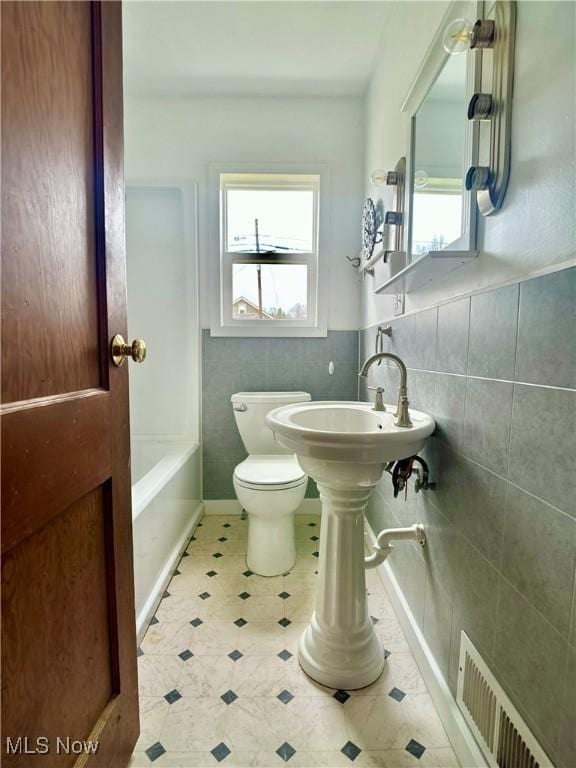 full bathroom with visible vents, plenty of natural light, tile walls, and toilet