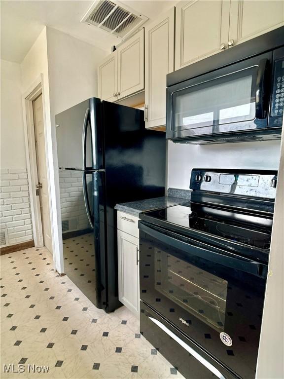 kitchen featuring visible vents, black appliances, a wainscoted wall, and white cabinetry