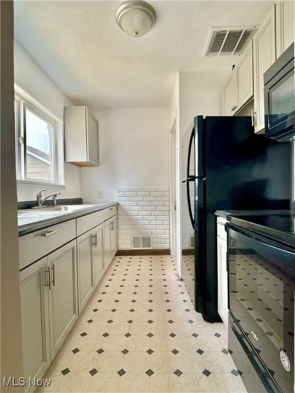 kitchen featuring a sink, visible vents, wainscoting, and black microwave