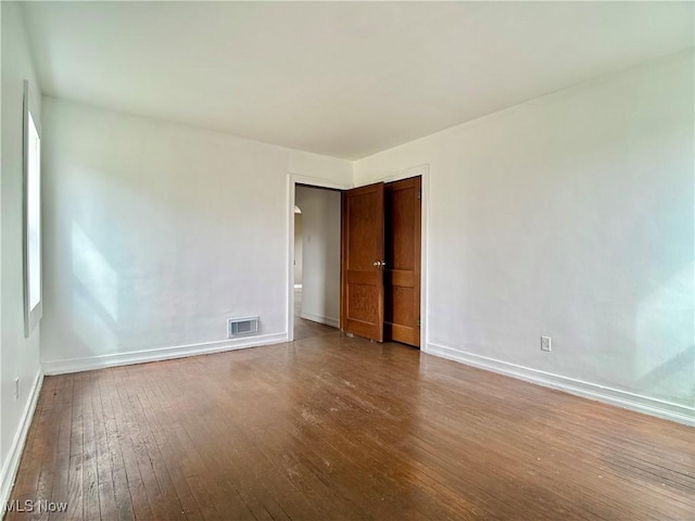 spare room featuring visible vents, baseboards, and hardwood / wood-style floors