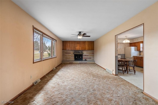 living room featuring light carpet, visible vents, ceiling fan with notable chandelier, and baseboards