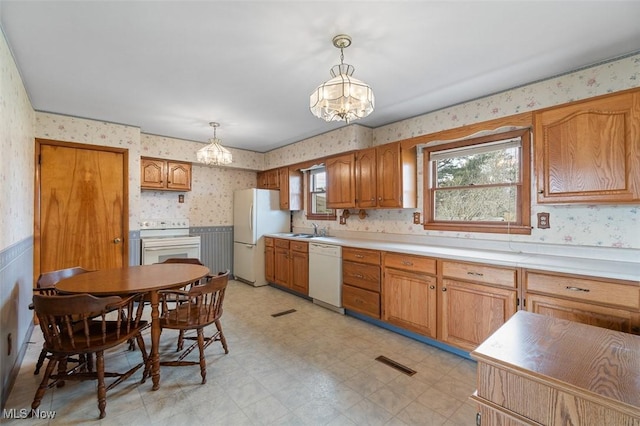 kitchen featuring white appliances, light floors, visible vents, wallpapered walls, and a sink