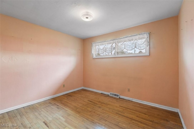 spare room featuring visible vents, baseboards, and hardwood / wood-style floors