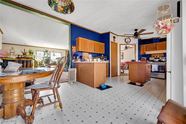 kitchen featuring ornamental molding, a ceiling fan, radiator heating unit, freestanding refrigerator, and stainless steel range with gas cooktop