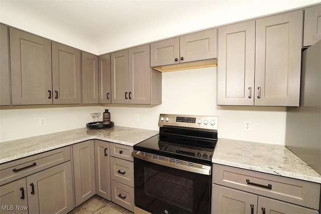 kitchen featuring light stone counters, electric stove, and gray cabinetry