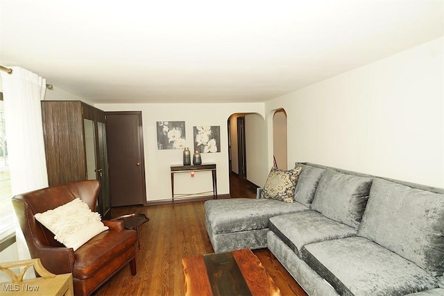 living room featuring arched walkways and dark wood finished floors