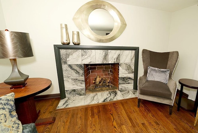 living area featuring a fireplace, baseboards, and wood finished floors