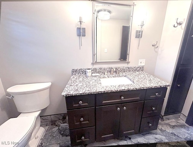 bathroom featuring toilet, marble finish floor, and vanity