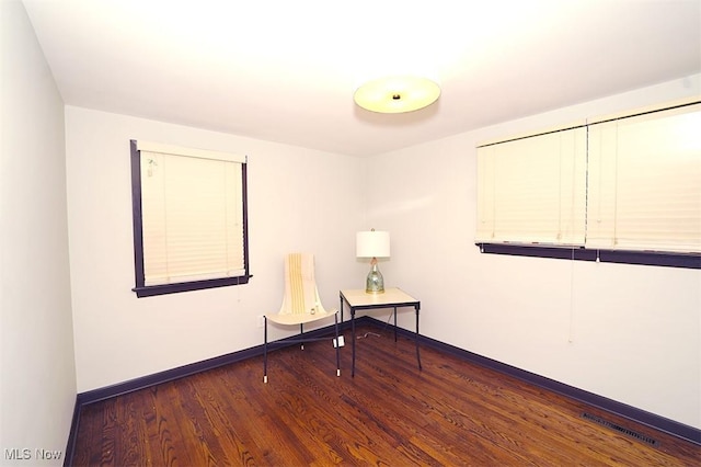 empty room with wood finished floors, visible vents, and baseboards