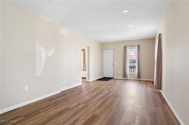 empty room featuring visible vents, baseboards, and wood finished floors