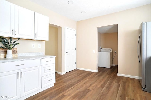 kitchen with light countertops, freestanding refrigerator, wood finished floors, washer / clothes dryer, and white cabinetry