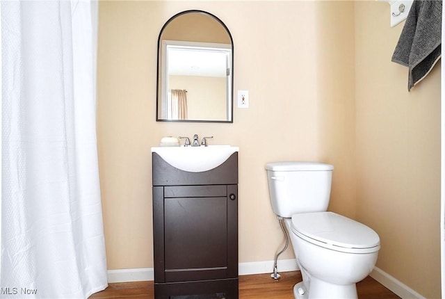 bathroom featuring vanity, toilet, wood finished floors, and baseboards