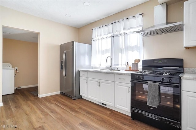 kitchen featuring a sink, black range with gas cooktop, wall chimney exhaust hood, stainless steel fridge with ice dispenser, and washer / dryer