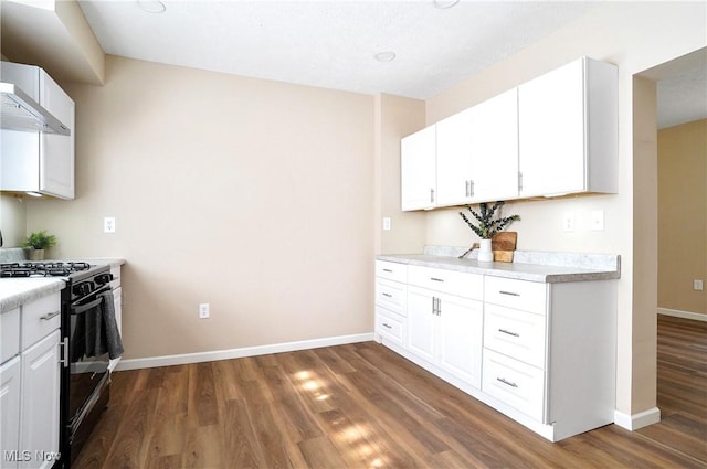 kitchen featuring light countertops, black gas range oven, dark wood-style flooring, and baseboards