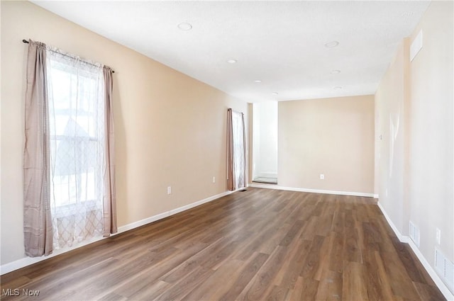 spare room featuring visible vents, wood finished floors, and baseboards