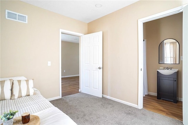 bedroom featuring a sink, visible vents, baseboards, and carpet flooring