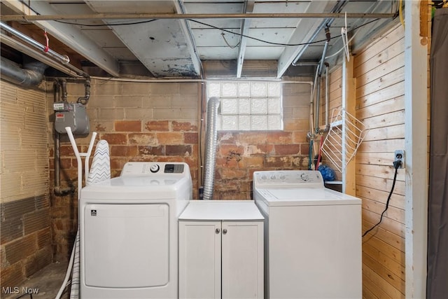 laundry area with cabinet space, independent washer and dryer, and wood walls