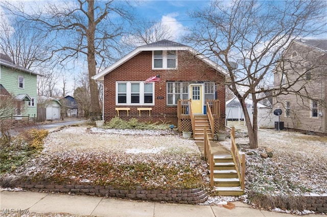 bungalow-style house featuring cooling unit, an outbuilding, brick siding, and fence