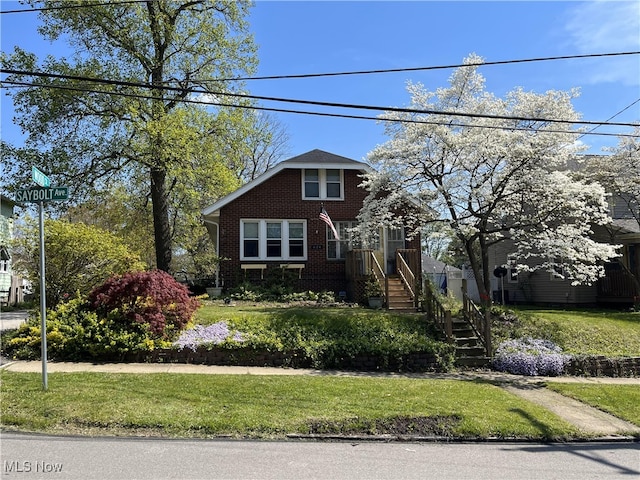 view of front facade with brick siding and a front lawn