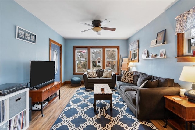 living room with light wood-type flooring, baseboards, and ceiling fan