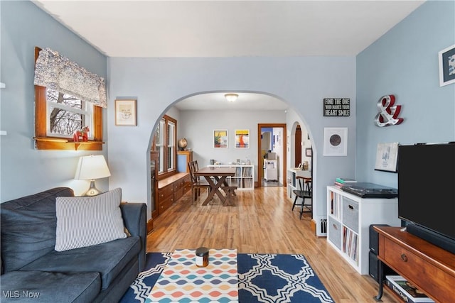 living room featuring arched walkways and light wood-style flooring