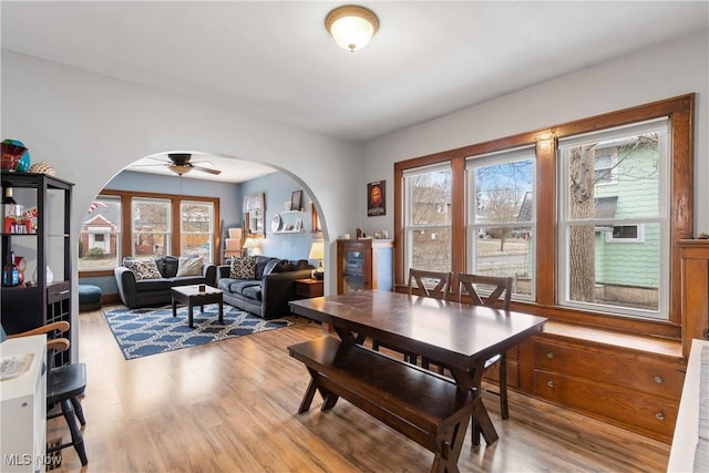 dining room with a ceiling fan, wood finished floors, and arched walkways