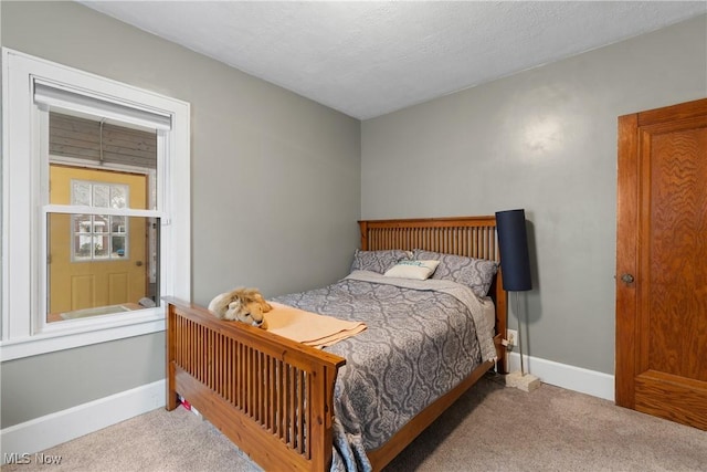 bedroom with carpet, baseboards, and a textured ceiling