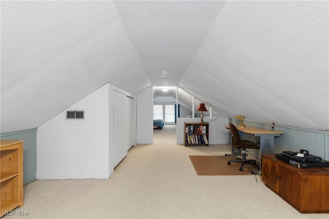 office space with visible vents, a textured ceiling, lofted ceiling, and carpet