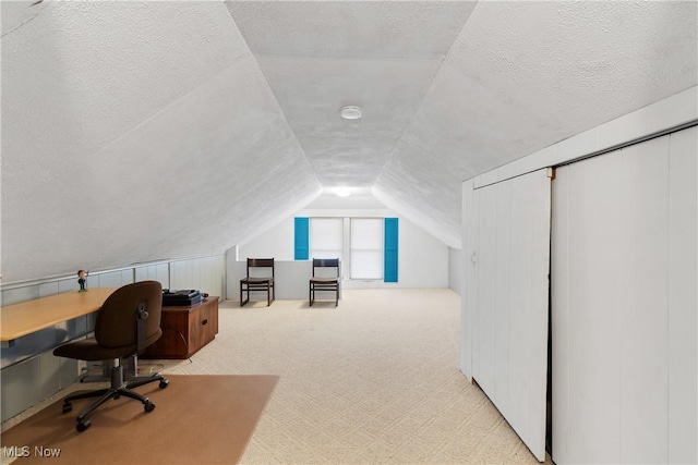 carpeted office featuring lofted ceiling and a textured ceiling