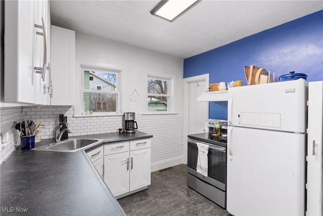 kitchen featuring electric range, freestanding refrigerator, a sink, white cabinets, and dark countertops