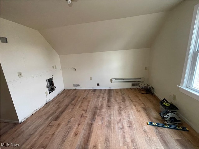 additional living space with visible vents, lofted ceiling, wood finished floors, and a baseboard heating unit