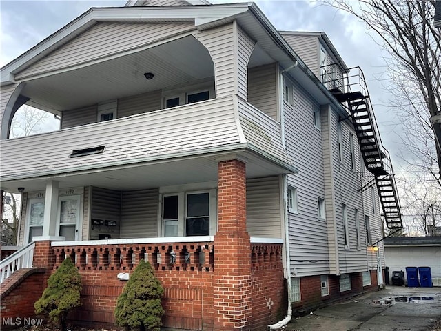 view of side of property with a garage, an outbuilding, a porch, and a balcony