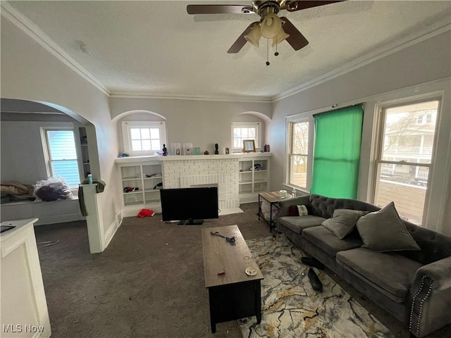 carpeted living room with baseboards, arched walkways, a textured ceiling, crown molding, and a brick fireplace