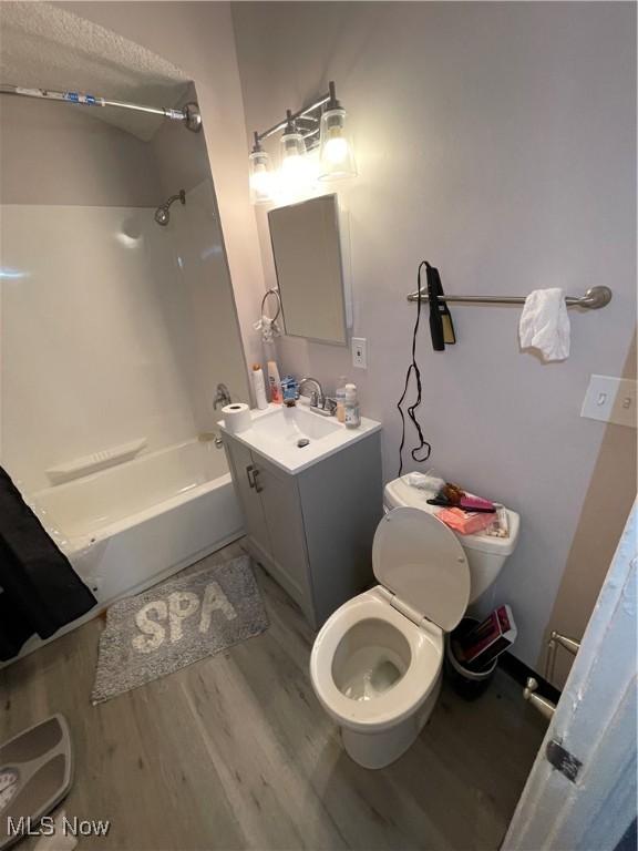 full bath with tub / shower combination, toilet, wood finished floors, and vanity