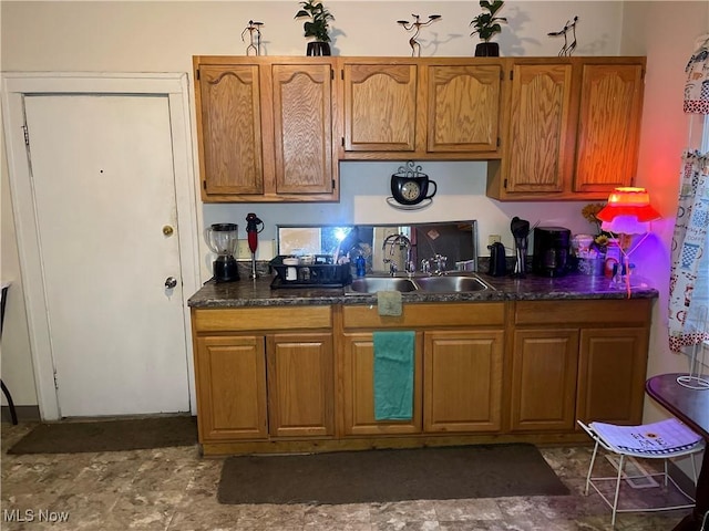 kitchen featuring dark countertops, brown cabinetry, and a sink