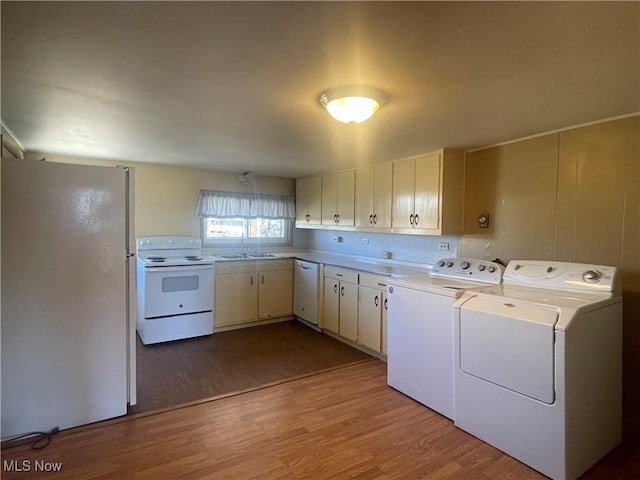 clothes washing area with washer and clothes dryer, laundry area, light wood finished floors, and a sink