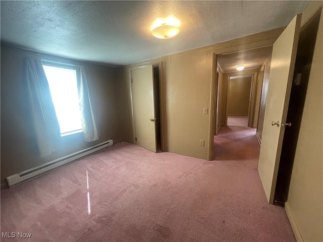 unfurnished bedroom with a baseboard heating unit, carpet floors, and a textured ceiling