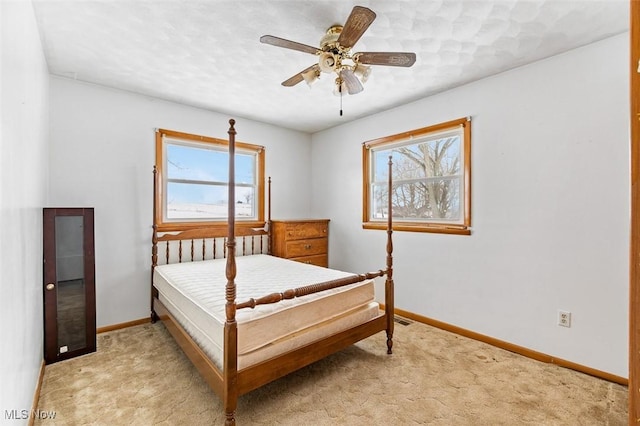 bedroom featuring light colored carpet, baseboards, and ceiling fan