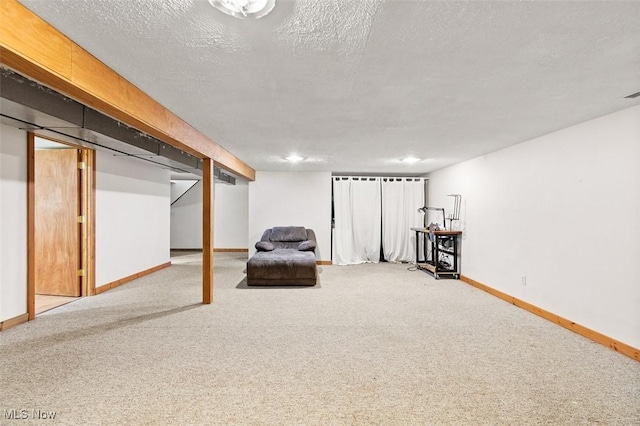 finished below grade area with baseboards, a textured ceiling, and carpet