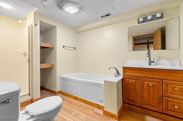 full bathroom featuring toilet, wood finished floors, vanity, and a bath