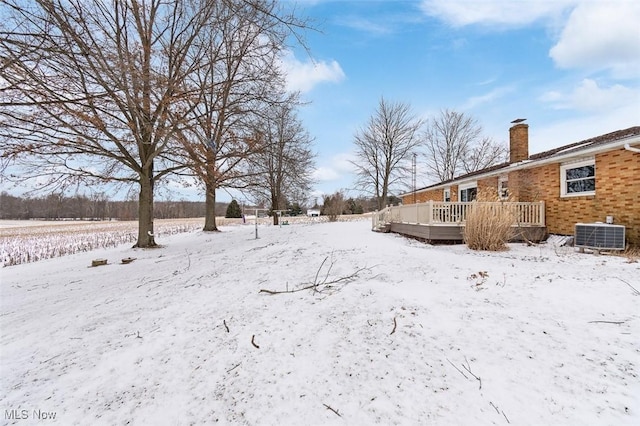 yard layered in snow with a wooden deck and central AC