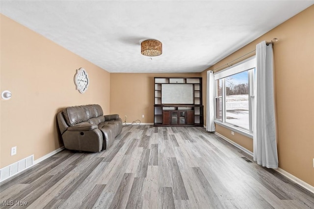 unfurnished living room with visible vents, baseboards, and wood finished floors