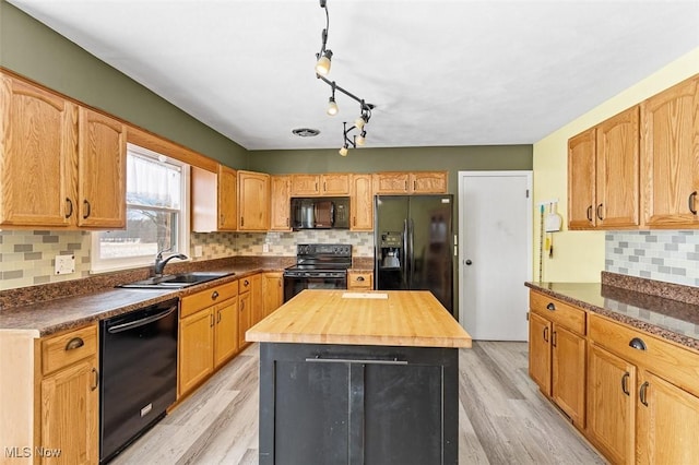 kitchen featuring wooden counters, black appliances, light wood-type flooring, and a sink