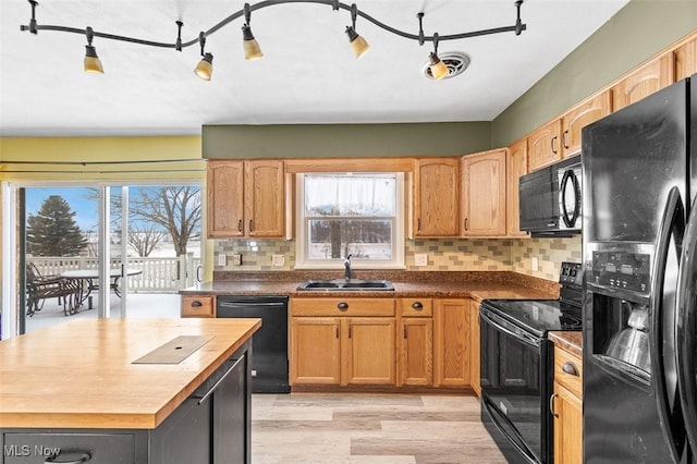 kitchen featuring visible vents, backsplash, butcher block countertops, black appliances, and a sink