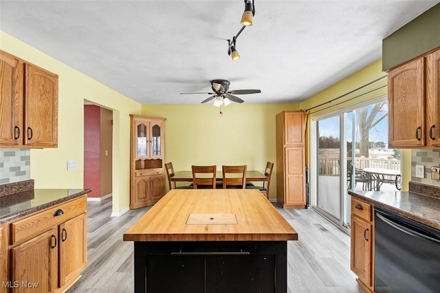 kitchen featuring baseboards, dishwasher, decorative backsplash, light wood-style floors, and wood counters