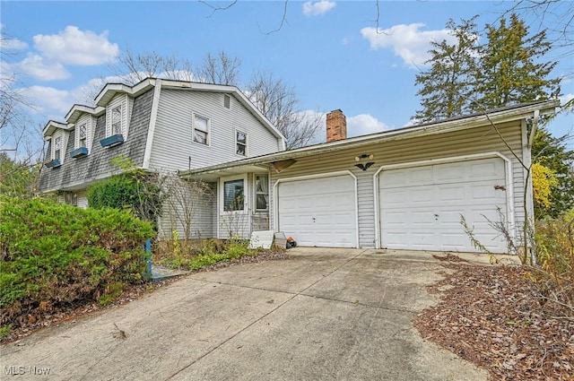 view of front of property with driveway, a chimney, and a garage