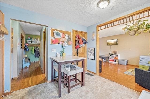 interior space featuring baseboards, wood finished floors, visible vents, and a textured ceiling