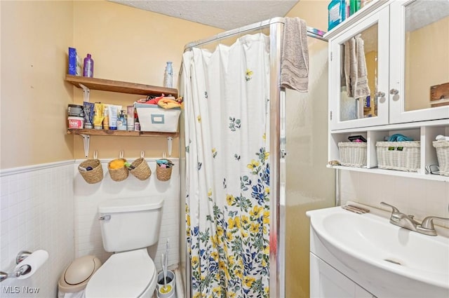 bathroom with wainscoting, a stall shower, toilet, and tile walls