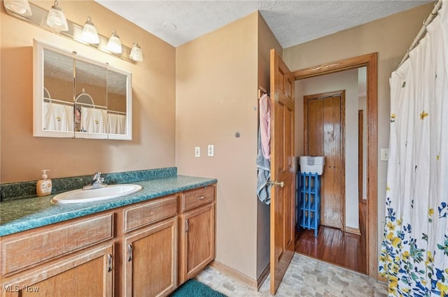 bathroom with vanity, baseboards, and a textured ceiling